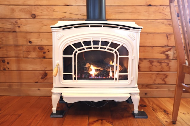 room details with a wood stove, wooden walls, and wood finished floors