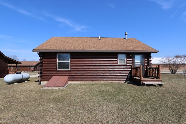 rear view of house with log siding, a yard, and roof with shingles