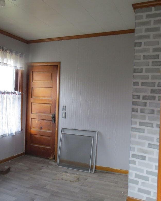 interior space featuring baseboards, wood finished floors, and crown molding