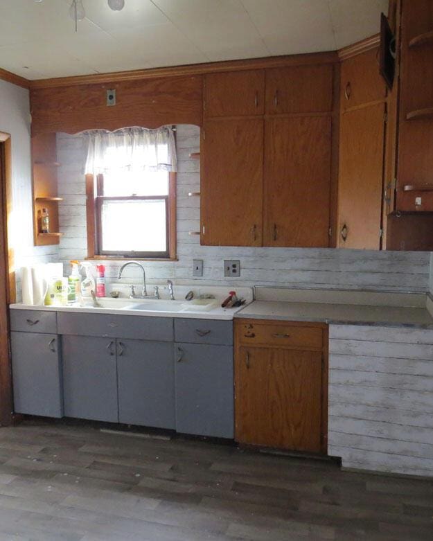 kitchen featuring a sink, crown molding, light countertops, and light wood finished floors