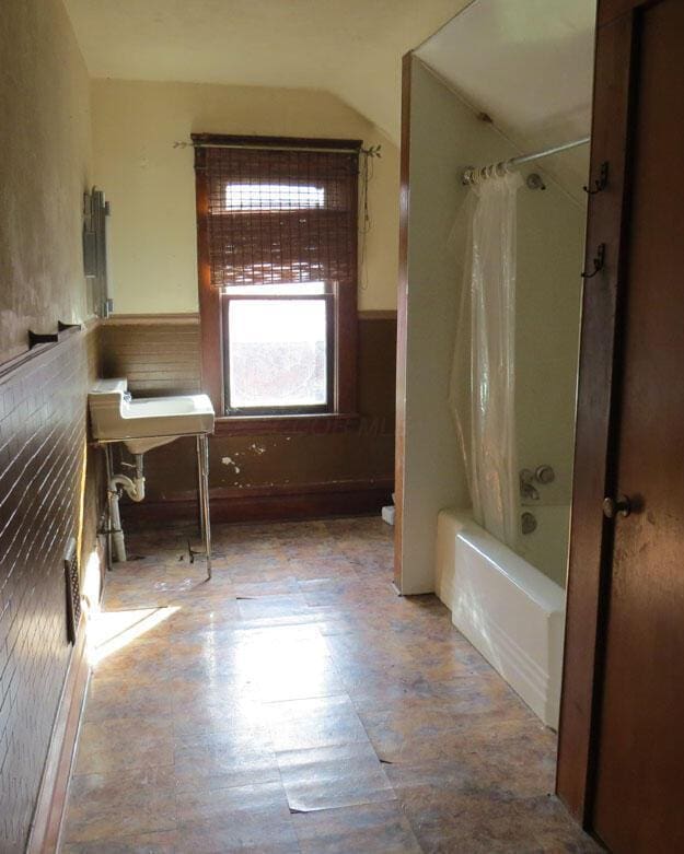 full bathroom with shower / tub combo and wainscoting