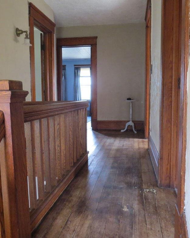 hall with dark wood-type flooring and baseboards