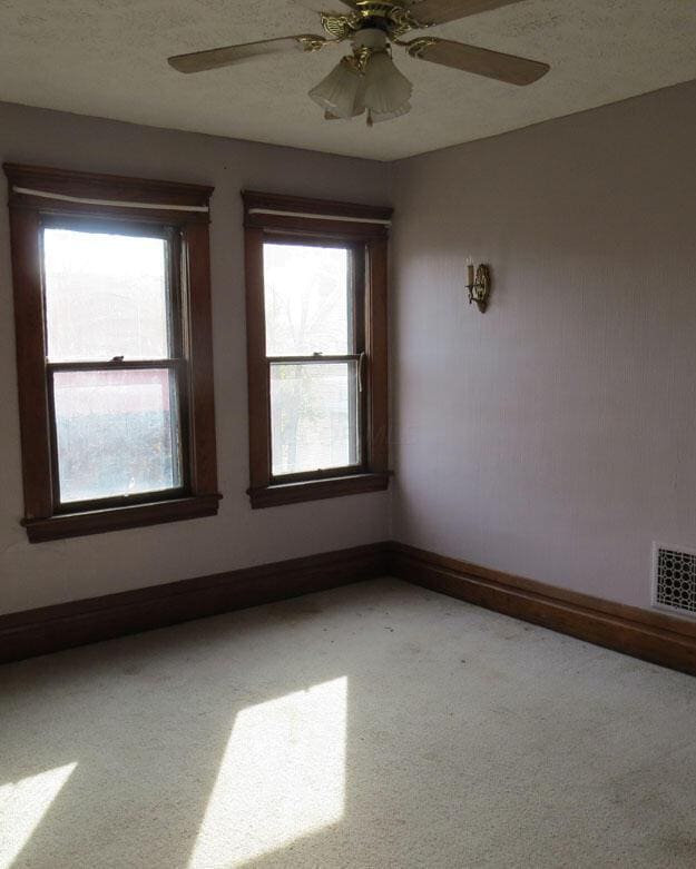 spare room featuring visible vents, plenty of natural light, a textured ceiling, and carpet floors