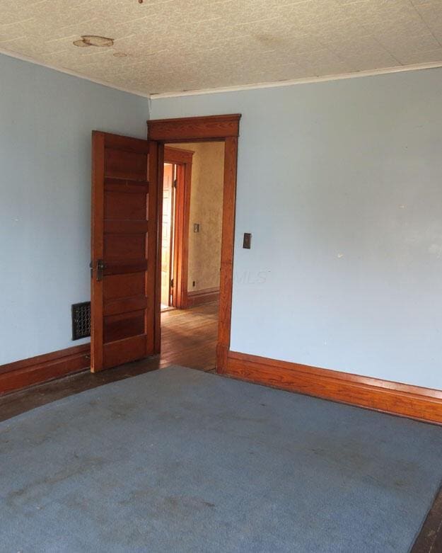 carpeted spare room featuring visible vents, baseboards, and a textured ceiling