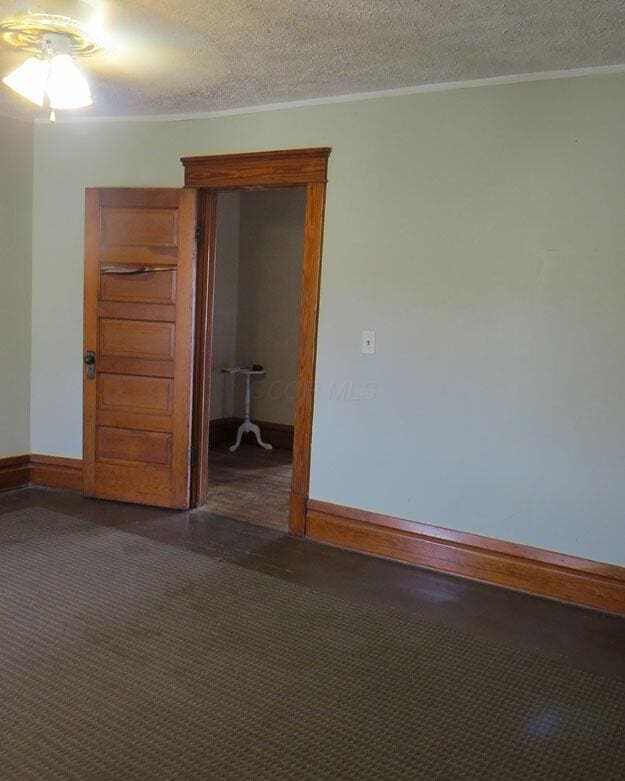 empty room with baseboards, a textured ceiling, and crown molding