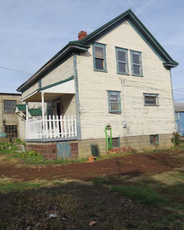 view of property exterior featuring covered porch and a chimney