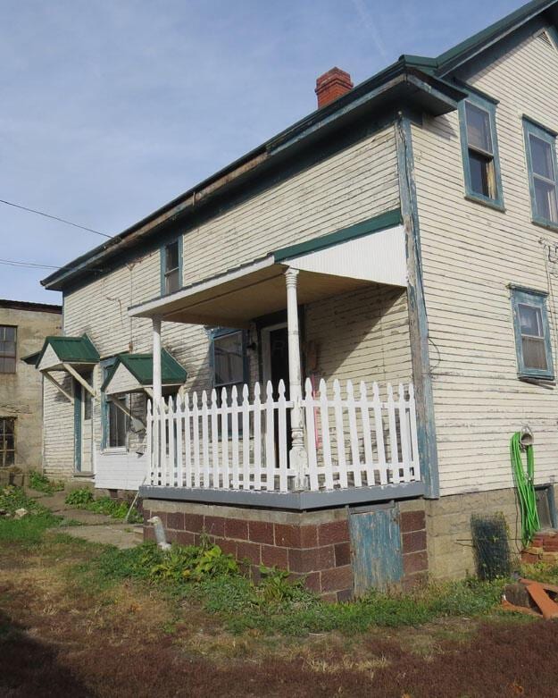 view of property exterior featuring covered porch and a chimney