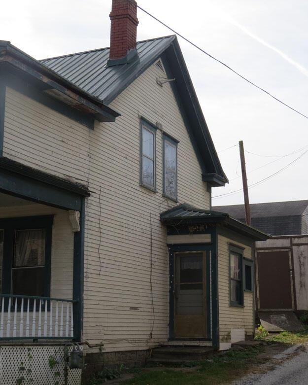 view of side of home with entry steps, a standing seam roof, a porch, metal roof, and a chimney