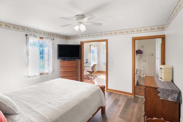 bedroom featuring connected bathroom, a ceiling fan, baseboards, and wood finished floors