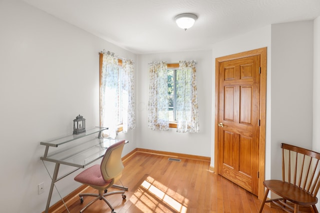 office area with visible vents, baseboards, and light wood finished floors