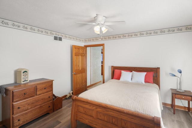 bedroom with baseboards, wood finished floors, visible vents, and ceiling fan