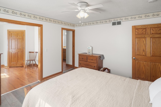 bedroom featuring visible vents, baseboards, wood finished floors, and a ceiling fan
