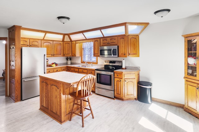 kitchen with a sink, stainless steel appliances, brown cabinets, and light countertops