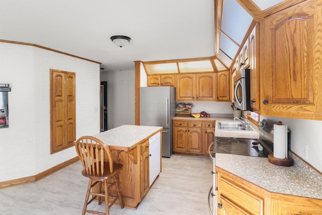 kitchen with brown cabinetry, appliances with stainless steel finishes, light countertops, and a sink
