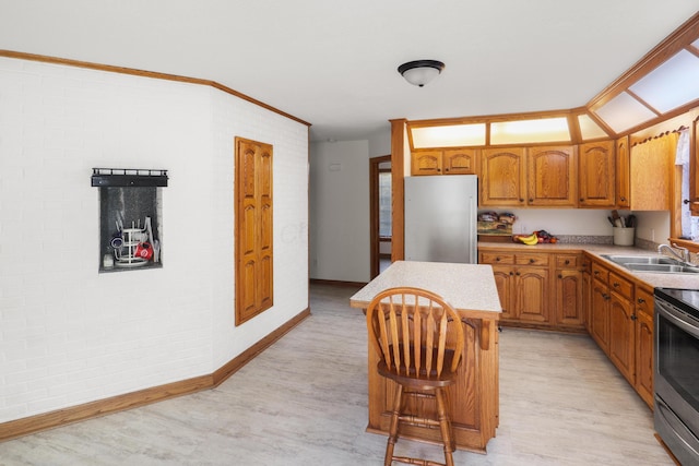 kitchen with a center island, light wood-style flooring, appliances with stainless steel finishes, brown cabinets, and a sink