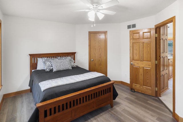bedroom featuring ceiling fan, wood finished floors, visible vents, and baseboards