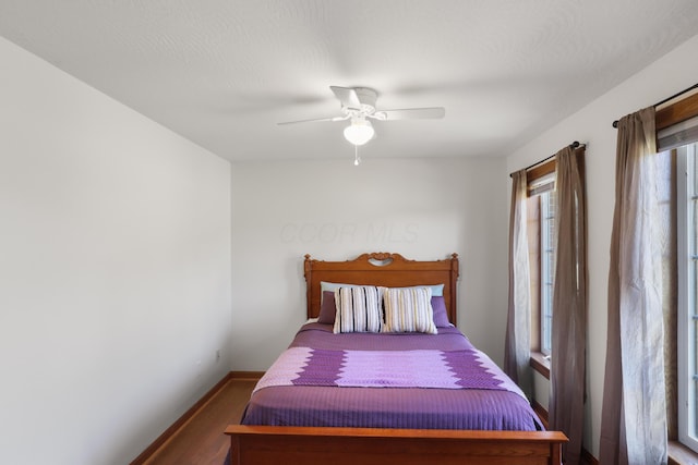 bedroom featuring a ceiling fan, baseboards, and wood finished floors
