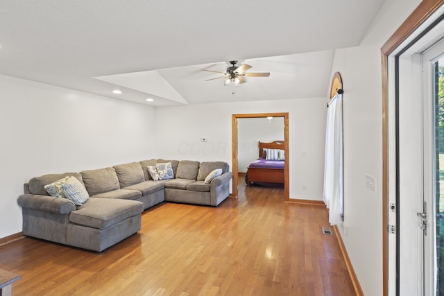 living area featuring visible vents, a ceiling fan, baseboards, and light wood finished floors