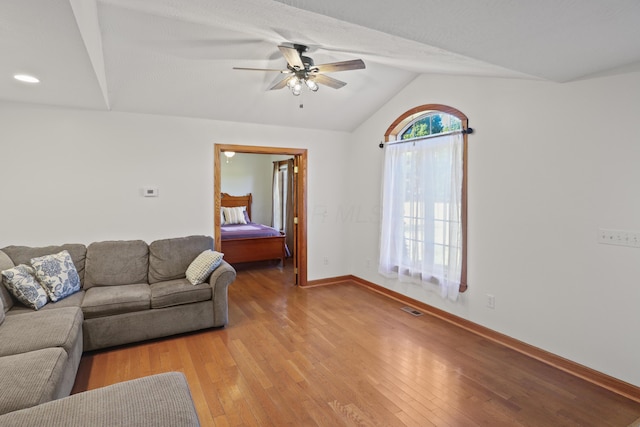 living room featuring visible vents, light wood finished floors, baseboards, ceiling fan, and vaulted ceiling