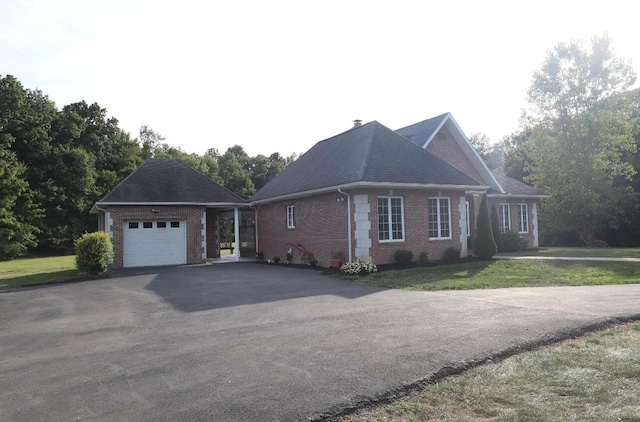view of side of home featuring an outbuilding, driveway, a yard, a garage, and brick siding