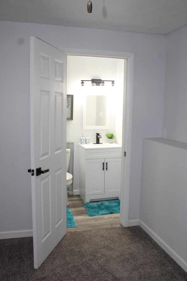 half bath featuring toilet, vanity, and baseboards