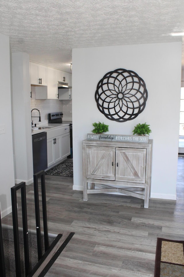 interior space with wood finished floors, electric range, a sink, decorative backsplash, and a textured ceiling