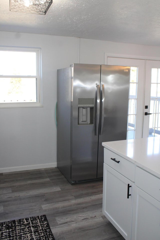 kitchen with light countertops, white cabinets, dark wood-style floors, stainless steel fridge, and a textured ceiling