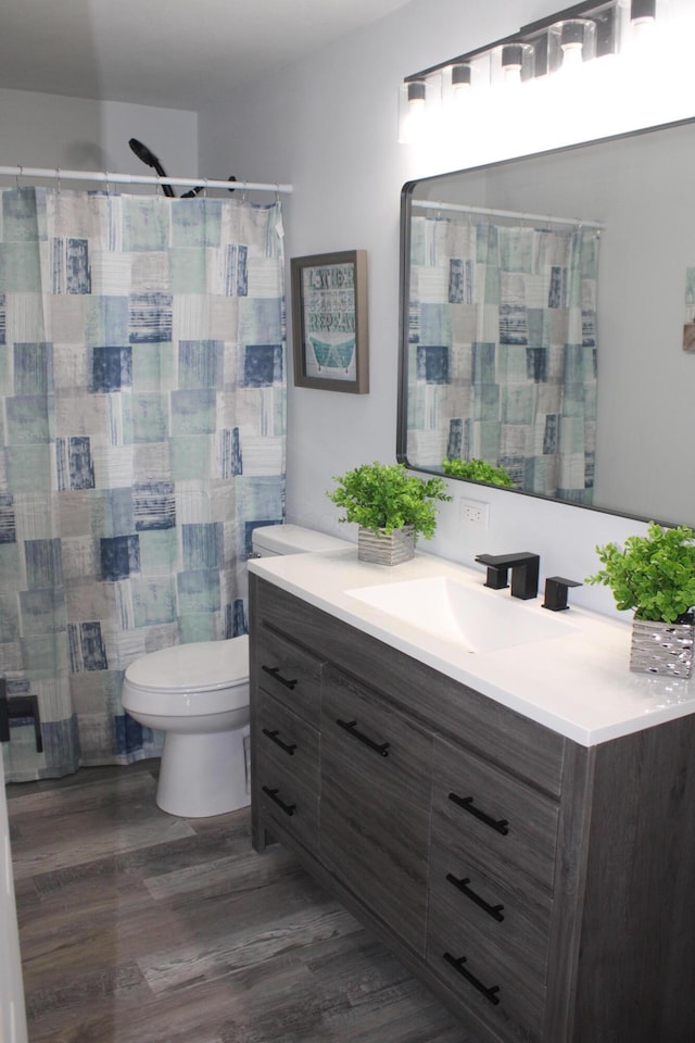 bathroom with vanity, curtained shower, toilet, and wood finished floors