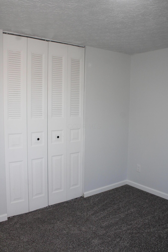 unfurnished bedroom with carpet, baseboards, a closet, and a textured ceiling