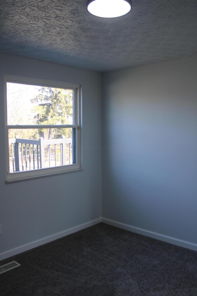 carpeted empty room featuring visible vents, a textured ceiling, and baseboards