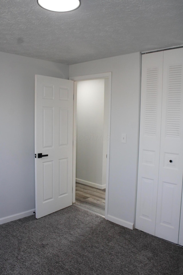 unfurnished bedroom with baseboards, a closet, a textured ceiling, and carpet