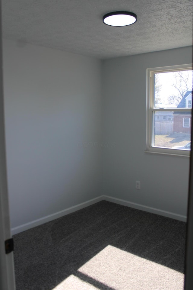 carpeted empty room featuring baseboards and a textured ceiling