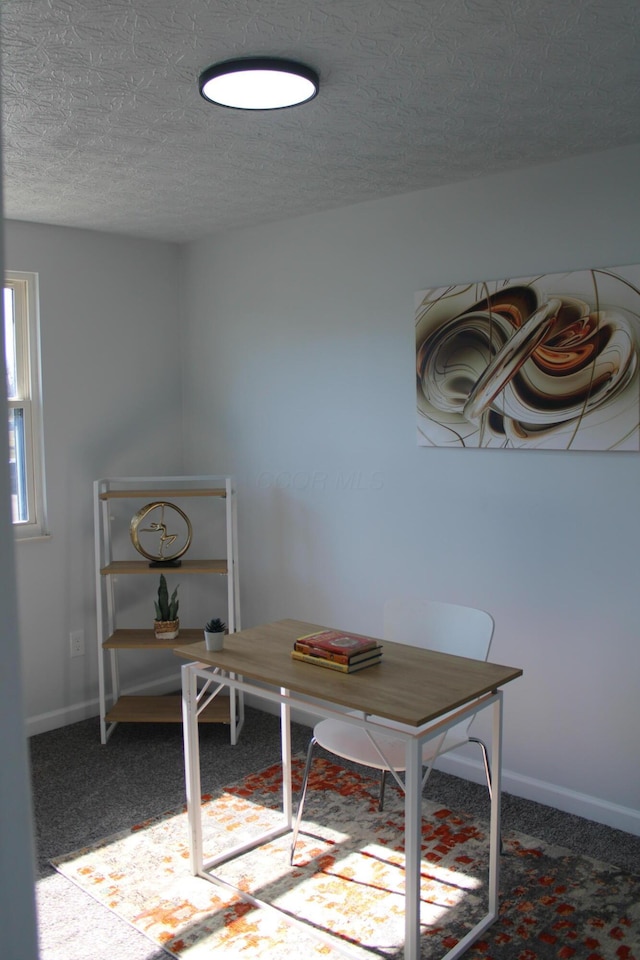 carpeted dining area featuring a textured ceiling and baseboards