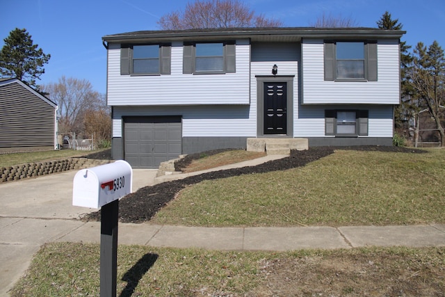 bi-level home featuring a front yard, a garage, and driveway