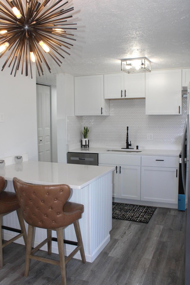 kitchen with dark wood finished floors, a breakfast bar, a sink, light countertops, and tasteful backsplash