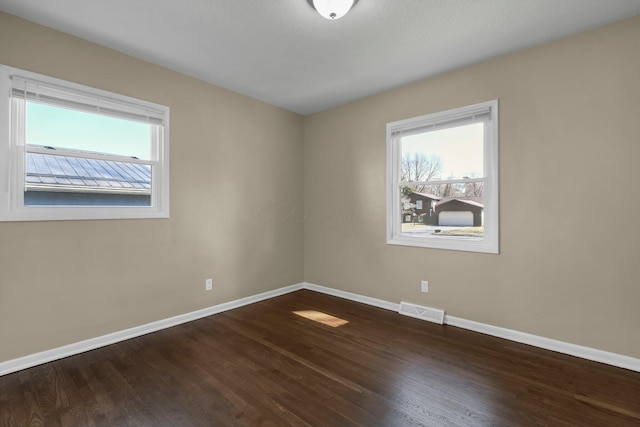 spare room with visible vents, baseboards, and wood finished floors