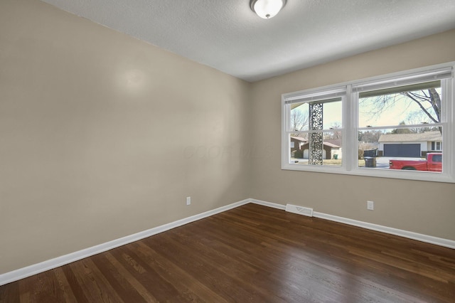 unfurnished room featuring visible vents, a textured ceiling, baseboards, and dark wood-style flooring