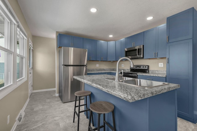 kitchen with blue cabinetry, stainless steel appliances, a breakfast bar area, and baseboards