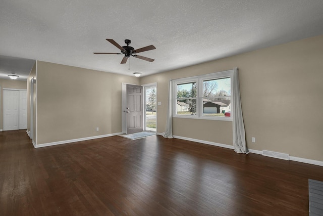 unfurnished room with baseboards, dark wood-style floors, visible vents, and ceiling fan