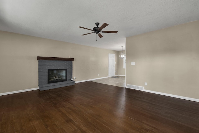 unfurnished living room with visible vents, wood finished floors, ceiling fan, and a fireplace