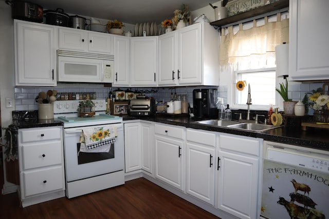 kitchen featuring white appliances, dark wood finished floors, a sink, white cabinets, and backsplash