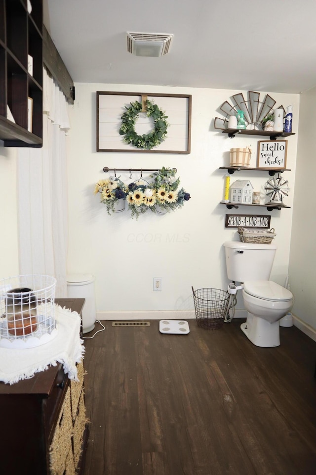 bathroom with toilet, wood finished floors, visible vents, and baseboards