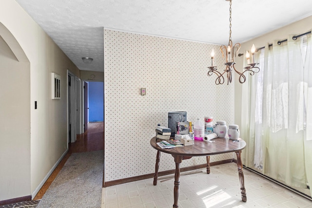 interior space featuring a textured ceiling, arched walkways, an inviting chandelier, wallpapered walls, and baseboards