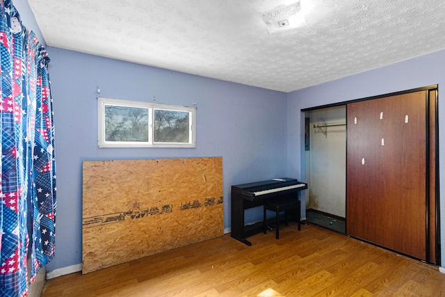 bedroom featuring a closet, baseboards, a textured ceiling, and wood finished floors