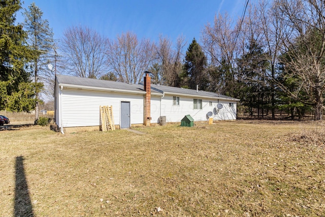 back of house with a chimney and a yard