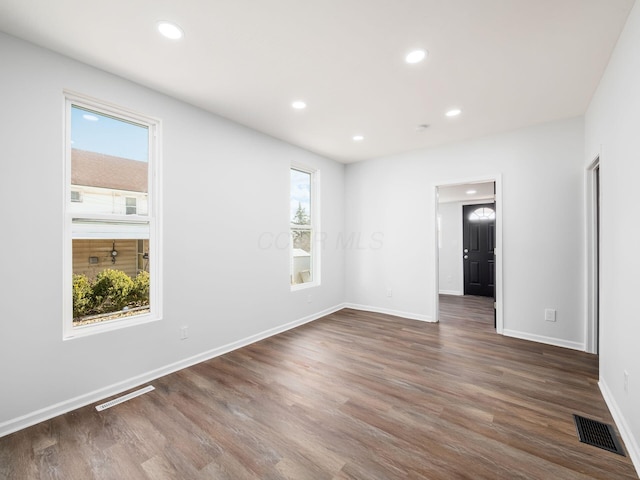 empty room with visible vents, recessed lighting, and dark wood-type flooring