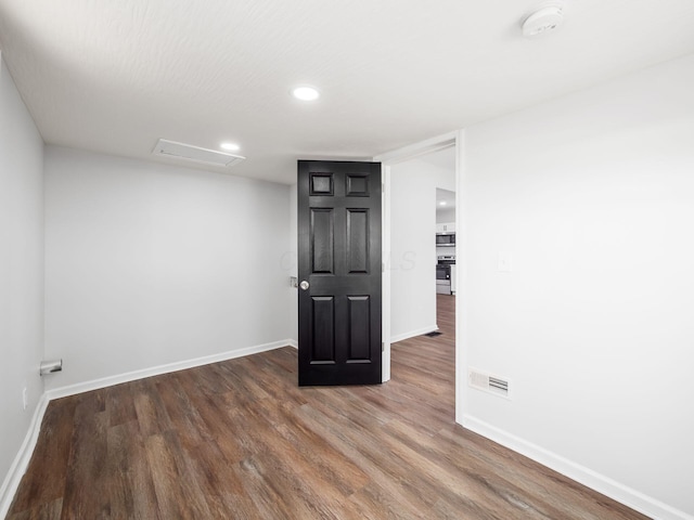 unfurnished room with visible vents, baseboards, attic access, recessed lighting, and wood finished floors