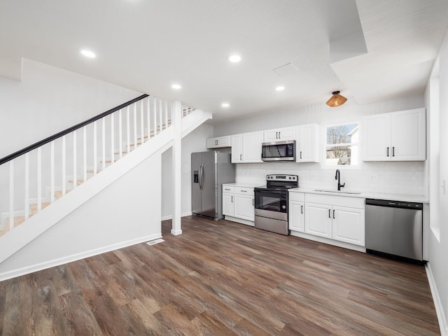 kitchen featuring a sink, dark wood finished floors, appliances with stainless steel finishes, white cabinets, and decorative backsplash