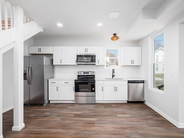 kitchen featuring backsplash, white cabinetry, stainless steel appliances, and a sink