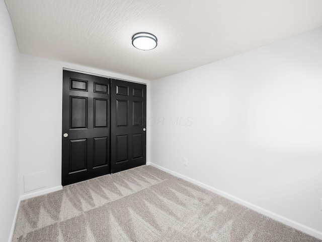 unfurnished bedroom with a closet, baseboards, and carpet floors